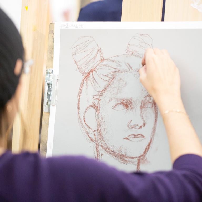 A woman sketching a face on an easel